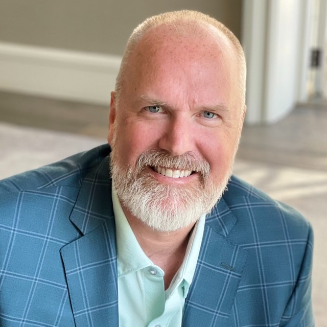 Chad Briscoe, smiling, in a blue plaid blazer